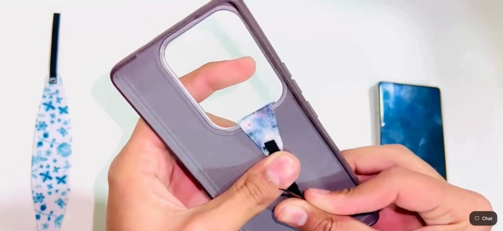 Hands sliding a grip strap under a phone case